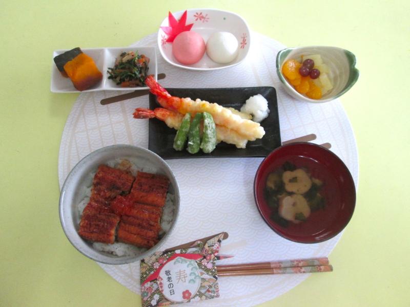 うな丼、天ぷら(海老・ししとう)、ほうれん草の胡麻和え、かぼちゃの煮物、フルーツ(みかん、ぶどう、パイン)、すまし汁、おやつの紅白饅頭